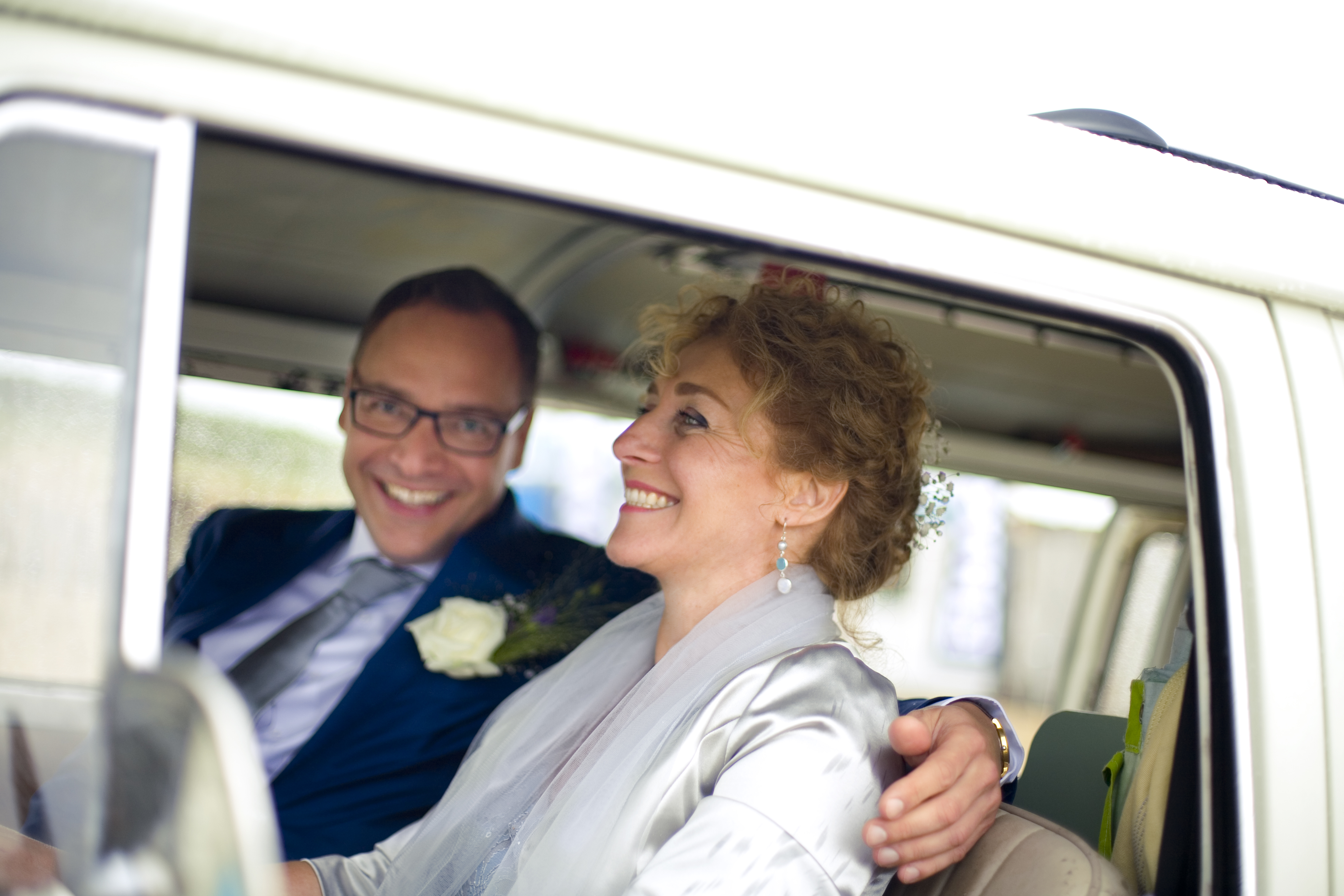 lachend Bruidspaar in Volkwagenbusje op huwelijksreis