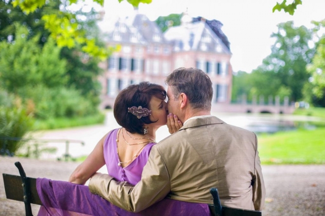 bruidspaar kus op bankje bij Kasteel Duivenvoorde Voorschoten met onscherpe achtergrond