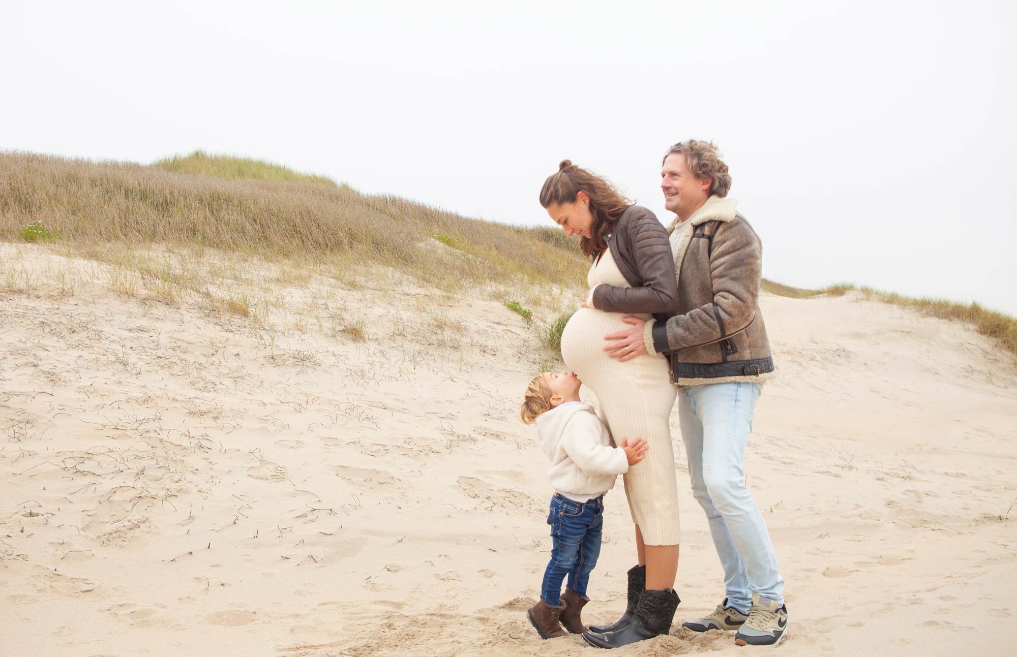 Foto zwangerschap vrolijke gezinsfoto familiefoto duinen spontane familiefotografie zwangerschapsfotografie Irene Den Haag